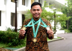 Juara dunia angkat besi kelas 61 kg Eko Yuli Irawa menunjukkan 3 medali emas yang baru diperolehnya, di Istana Merdeka, Jakarta, Kamis (8/11) pagi. (Foto: Rahmat/Humas) 