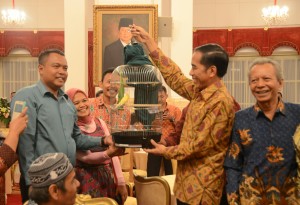 Presiden Jokowi mengangkat burung kenari hadiah yang diberikan pedagang tradisional yang telah diundangnya makan siang, di Istana Negara, Jakarta, Kamis (3/9) siang