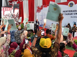 Presiden Jokowi menghitung sertfikat yang dipegang masyarakat dalam acara penyerahan 5.000 sertifikat untuk warga Jatim, di Jatim Expo, Surabaya, Kamis (6/9) siang. (Foto: BPMI Setpres)