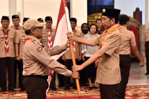 Presiden Jokowi menyerahkan bendera Merah Putih kepada ketua kontingan saar melepas delegasi Pramuka Indonesia pada Jambore Pramuka Dunia, di Istana Negara, Jakarta, Jumat (19/7) pagi. (Foto: Rahmat/Humas)